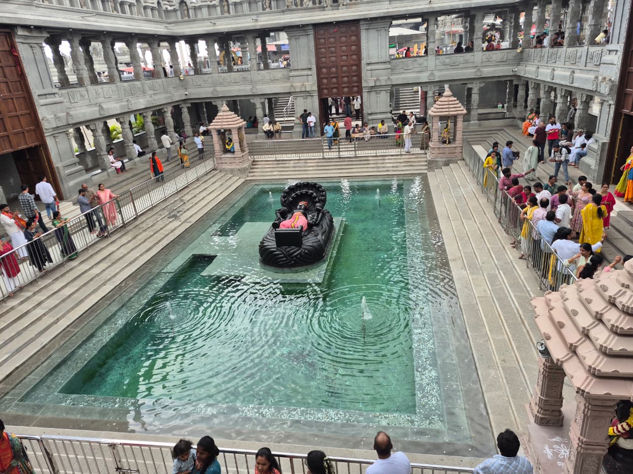Wide view of the Jala Narayana pool at Swarnagiri, surrounded by stepped edges, carved galleries and visitors.