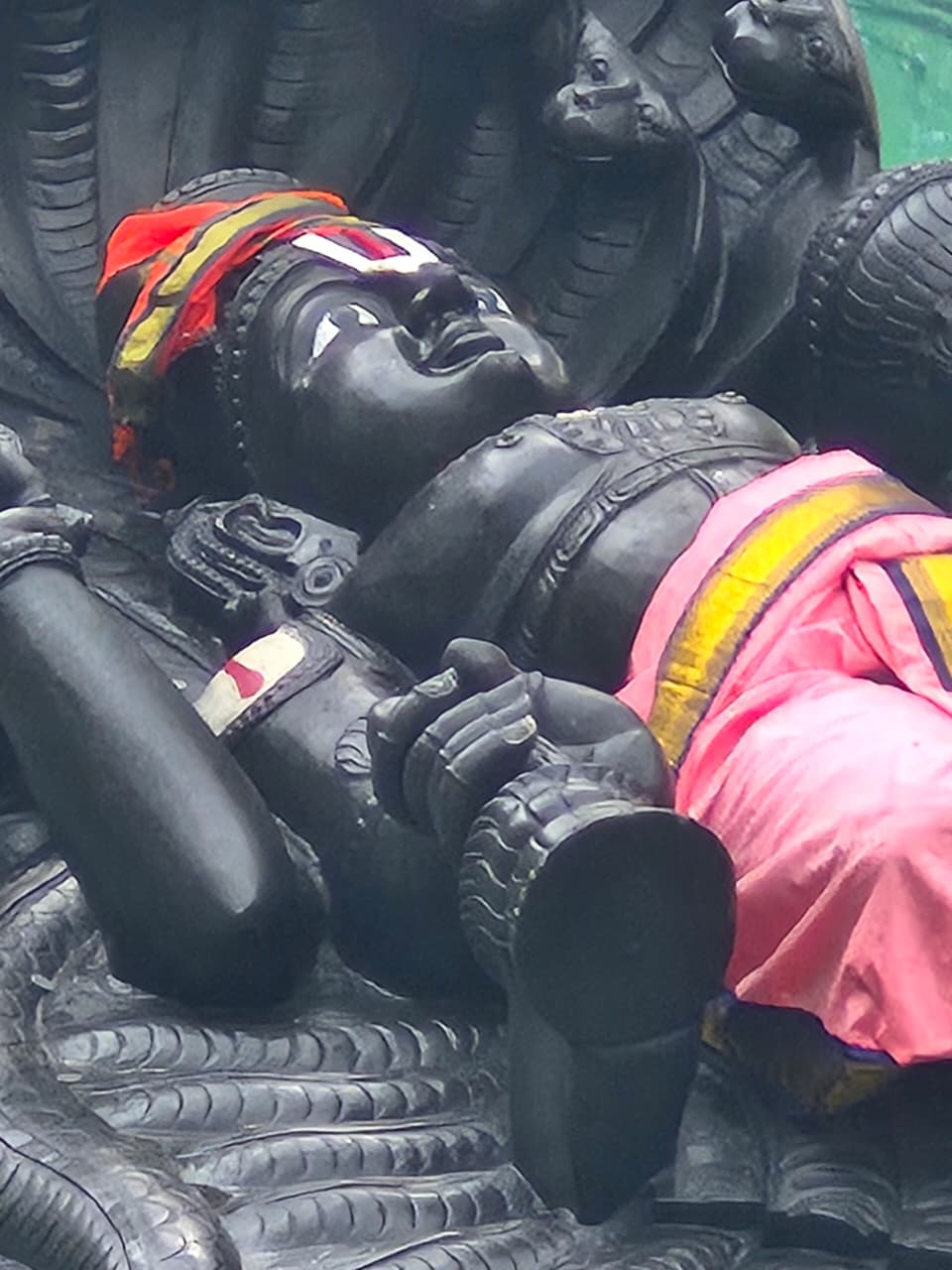 Close-up of Narayana’s face and painted forehead mark beneath raised serpent hoods.